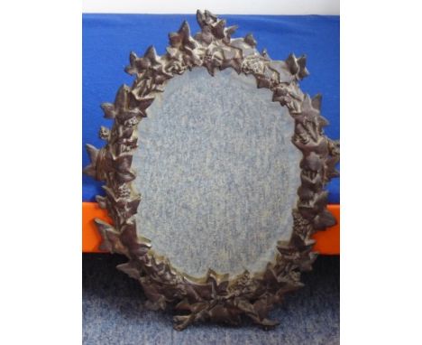 A 19th Century oval wall hanging looking glass having hand bevelled plate and patinated iron frame decorated with leaves and 