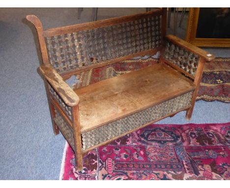 A late 19th century Arts and Crafts aesthetic-style two-seater walnut settle; the underside of one arm stamped Liberty & Co.,