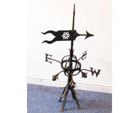 A wrought iron weather vane; pierced arrow head above E, S and W pointers (the N (for north) now missing) and further over op