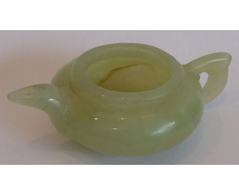 A Qing dynasty celadon nephrite jade pouring vessel having spout and handle; raised on short circular foot, length 9.5cm (fro