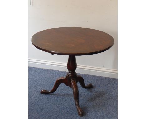 A George III period circular mahogany tilt-top occasional table, baluster turned stem and on tripod base with elongated pad-s