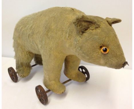 Antique/vintage mohair pull-along teddy bear on wheels. Mohair coat very worn and one eye missing.  On metal wheels each with