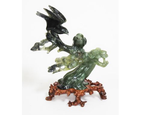 A Chinese spinach jade carving depicting two birds sat amongst a flowering prunus tree, carved wooden base, height 24cm.  
