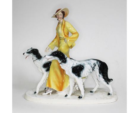 An Art Deco Goldscheider style figure of a woman walking two borzoi dogs, height 35cm and width 37cm. Condition:- There is a 