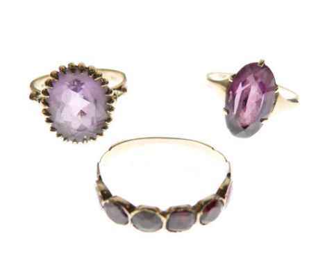 Three assorted gold and yellow metal rings, each set amethyst-coloured stones, comprising two single-stone examples, 9ct gold