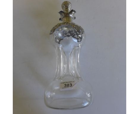 A Victorian silver topped glass decanter the glass of baluster form, topped with pierced and embossed scroll and foliate deta