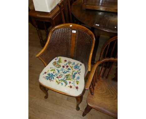 A 1920's cane work armchair with tapestry seat.