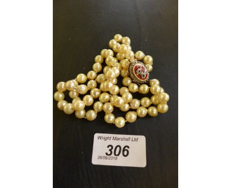 A string of pearls to a yellow metal and enamel set clasp, gross weight 60g