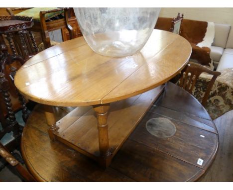 A light oak oval drop leaf coffee table with under tier, raised on turned supports.