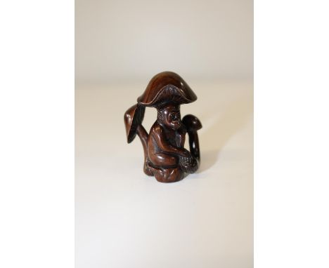 A box wood netsuke in the form of a sheltering monkey
