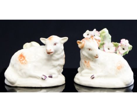 A pair of Derby models of recumbent sheep, 18th Century, both beside stumps, one florally encrusted, patch mark bases, height