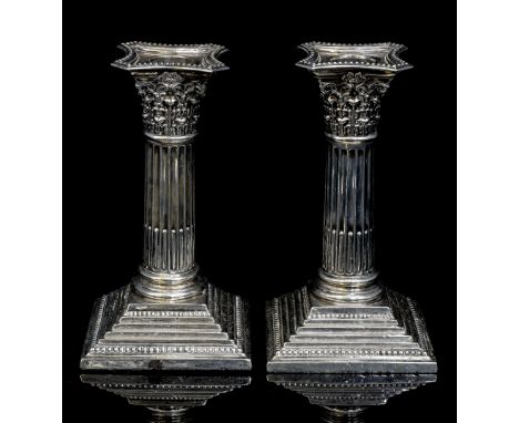 A pair of George V silver loaded candlesticks, of Corinthian form with foliate detail on stepped base with beaded edges, remo