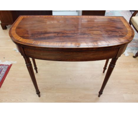 A George III mahogany and satinwood cross-banded fold-over card table, circa 1810, raised on turned tapering legs
