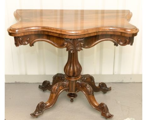 A George III rosewood card table, c.1810, serpentine fronted, carved frieze, raised on a baluster and reeded turned column, s