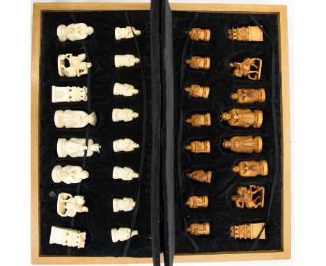 An oriental ivory chess set, 20th Century, white and tan stained playing pieces, carved as figures and temples, signed, in a 