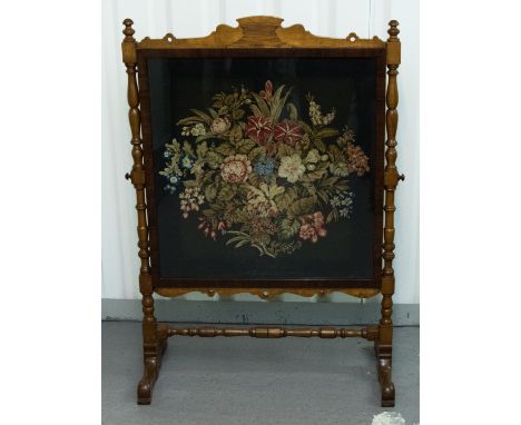 A late Victorian oak framed firescreen, c.1880, fitted with a woolwork panel, turned stretcher, 110cm high, 78cm wide