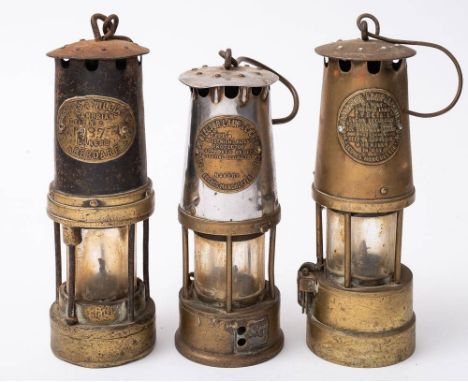 A brass miners lamp by Thomas Wilkins, Aberdare, No. 287,: together with two other lamps by  The Protector Lamp &amp; Lightin