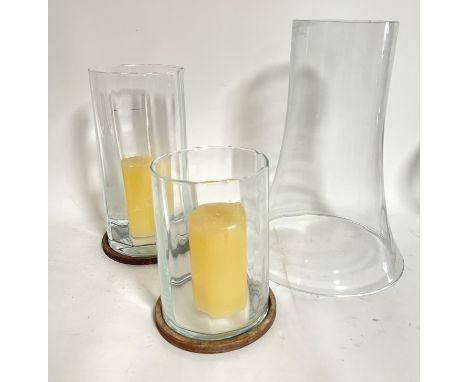 A pair of round storm lantern glass candleholders with plaster bases of differing heights (h. x 31 cm d. x 14.5 cm, h. x 22 c
