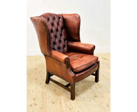 A good mahogany framed Georgian style distressed leather button back wing/club chair (h.110cm x l. 78cm x w.85cm)