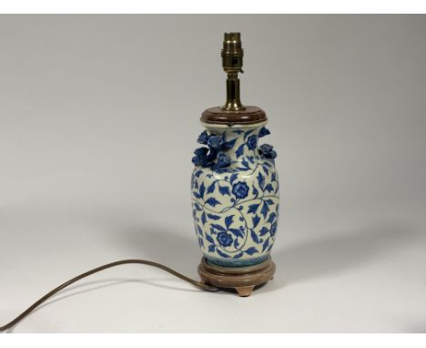 A blue and white Chinese table lamp decorated with moulded chrysanthemum flowerheads to neck raised on a circular wooden base