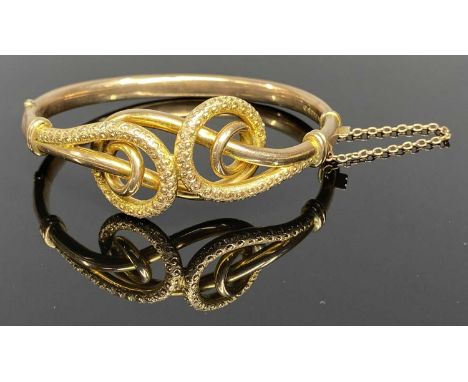 CHESTER 1907 9CT GOLD HOLLOW CORE BANGLE by Joseph Hawkins, the top having an openwork design of two twisting scrolls with a 