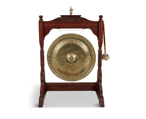 AN EDWARDIAN STAINED OAK AND BRASS DINNER GONG AND BEATER, of architectural form, surmounted by fleur de lis brass finial, ra