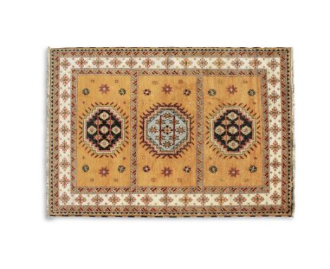 A KONYA ORANGE GROUND RUG, Turkey, the central reserve divided into three sections, each containing a medallion, in navy, lig