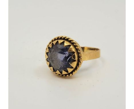 A precious yellow metal and light blue stone dress ring, claw set mixed round cut light blue stone within wire work border (y