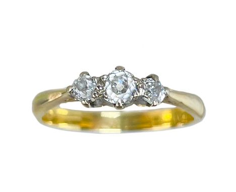 An 18ct and platinum diamond set three stone ring. The central round old brilliant cut diamond of 0.15ct, flanked by two ston