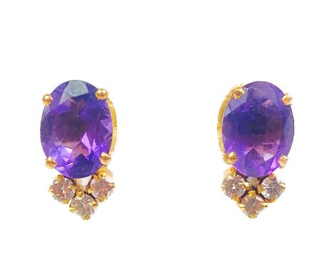 A pair of 18ct amethyst and diamond set screw back earrings. The oval cut amethysts measuring 7.8 x 6mm, each with three roun