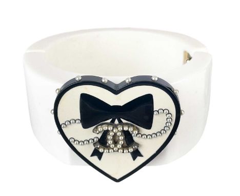 A Chanel CC heart and bow applied, white and black resin cuff hinged bangle, circa 2006. From the Spring collection, the appl