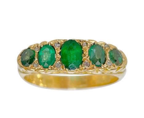 An Edwardian 18ct emerald set five-stone ring. The central oval green paste stone measuring 5.5 x 4mm, flanked by four smalle