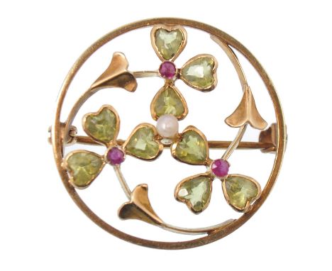 An early 20th century yellow 15ct gold and peridot, pearl and ruby Art Nouveau roundel brooch. The stones in floral openwork 
