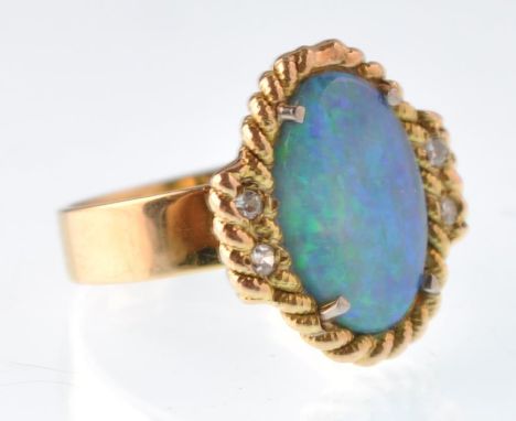 A modern black opal and diamond&nbsp; gold dress ring. Centred with an oval black opal cabochon within a rope twist surround 