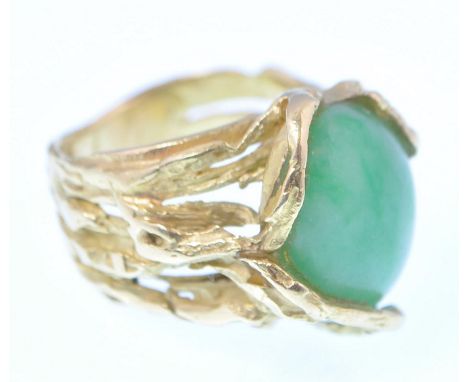 A 1970's French 18ct gold and jade ring. The ring being formed in a naturalistic design encasing a large natural jade cabocho