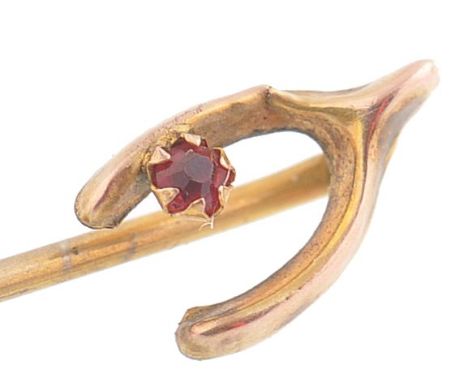 A 9ct gold and ruby stick wish bone adorned stick pin. The wishbone with claw mounted ruby. Total weight 0.58g / length 5.5cm