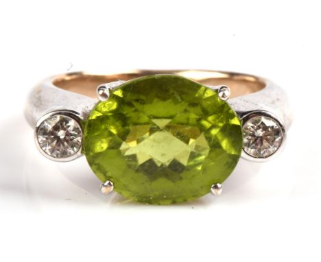 Peridot and diamond ring, with central claw set oval cut peridot weighing an estimated 5.29 carats, flanked either side by a 