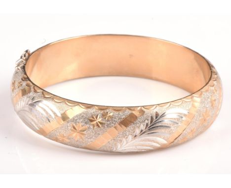 Gold hinged bangle, 16mm wide, with engraved detail to the full hoop, with a box clasp and two safety clips, stamped 9 ct, in
