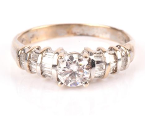 Diamond ring in white metal stamped "18CT" and "750", set with a principal round brilliant cut diamond, with tapered baguette