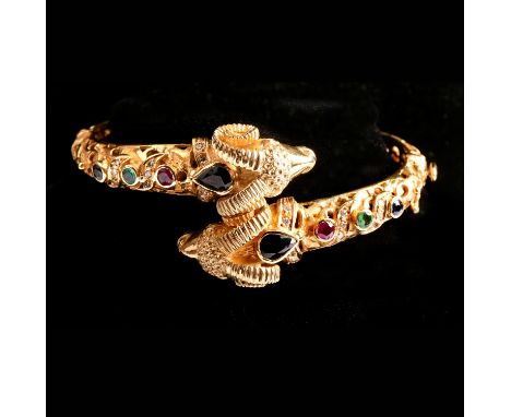 A gold and gem set ram head hinged bangle, designed as two rams heads, in a crossover position, each set with a pear cut sapp