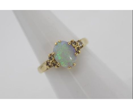 An 18ct gold, opal and diamond ring, central white opal with flashes of blue and green flanked by three small diamonds to eac