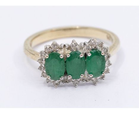 An emerald and diamond 9ct gold cluster ring, comprising three small clusters set in a row, claw set central oval cut emerald