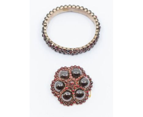 A Victorian garnet set gilt metal brooch, circular form set to the centre with  rose cut garnet with radiating star decoratio