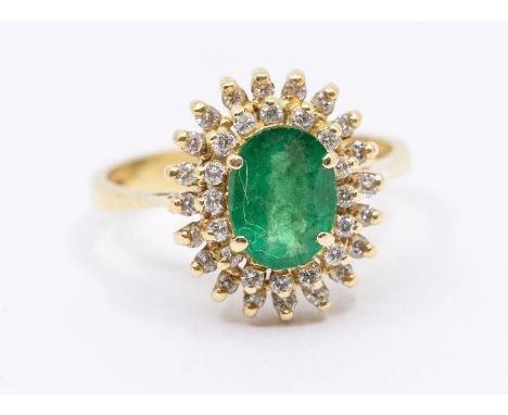 An emerald  and diamond 18ct gold cluster ring, comprising a claw set central oval cut emerald approx 7 x 5mm, within a doubl