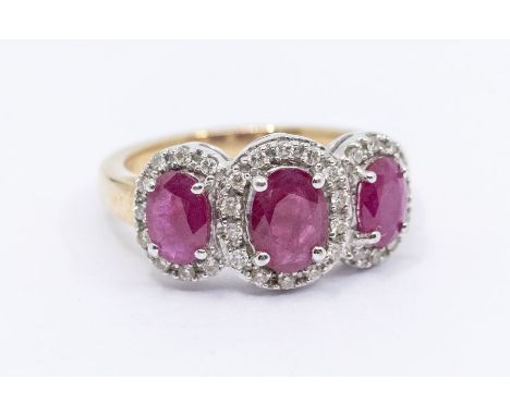 A ruby and diamond 9ct gold cluster ring, comprising three small clusters set in a row, claw set central oval cut ruby within