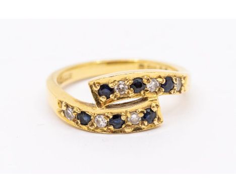 A diamond and sapphire 18ct gold cross over ring, the top with curved cross over set with alternate round sapphires and brill