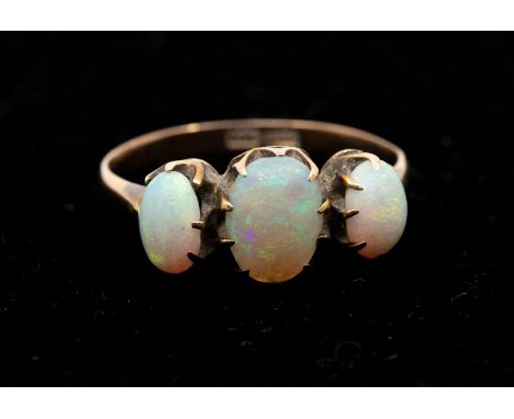 An opal and 9ct gold three stone ring, comprising three oval graduated opals, claw set in rose gold, the centre opal with gre