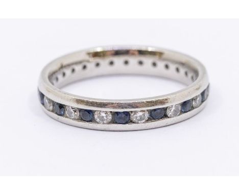 A sapphire and diamond platinum eternity ring, comprising alternate round cut sapphires and brilliant cut diamonds, channel s