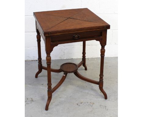 An oak card table with four triangular fold-out leaves, inset green baize and counter wells to top, on stretchered supports w