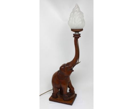 A wooden table lamp modelled as an elephant with frosted glass shade in the form of a flame, height approx 81cm. CONDITION RE